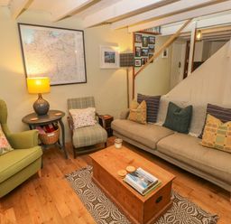 A living room with a green armchair and a beige sofa with patterned cushions at 2 Summerhill in Letterston