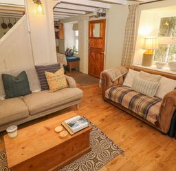 A living room with two sofas a wooden coffee table a table lamp and a wooden door at 2 Summerhill in Letterston
