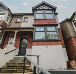 The front entrance of a two-story house with steps leading to a dark green door and large windows at Thirty Four By the Sea in Scarborough