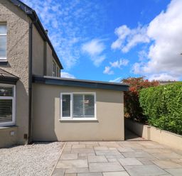 The side of a house with a paved patio area and gravel next to a hedge and shrubs at 3 Palms in Preston Sands