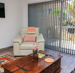 A living room with a leather armchair a wooden coffee table and vertical blinds at 3 Palms in Preston Sands