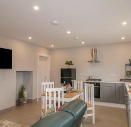 A kitchen and dining area with a dining table set for four and a black refrigerator at ARD NA GHAOITHE in Loughanure County Donegal