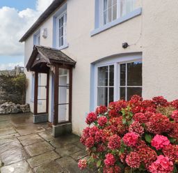 An exterior view of a house with a stone patio and red hydrangea flowers outside Holborn Cottage Blencathra Street Keswick