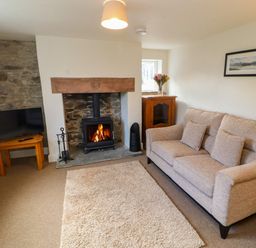 A living room with sofa a rug a fireplace and a television at Holborn Cottage Blencathra Street Keswick