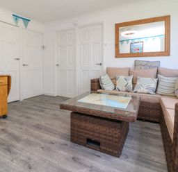 A living room with a wicker corner sofa and glass coffee table near white doors at 4 The Park in Kilkhampton