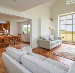 A living room with two sofas a rug and a large window overlooking a garden at West Dairy near Newport Pembrokeshire