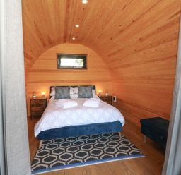 A bedroom with a double bed blue pillows bedside tables lamps and a geometric rug at Hawkstone in Kenstone near Hodnet