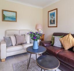 A living room with two sofas and a vase with flowers on a table at Seaweed in Weston near Sidmouth