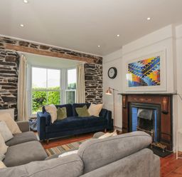 A living room with a blue sofa and a fireplace at 2 Glyddins 1910 in Rock