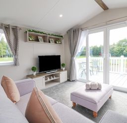 A living room with sofas a television and sliding glass doors opening to a patio at Stork Lodge in Swannington near Coalville