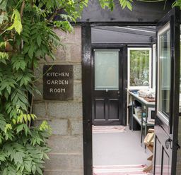 A doorway with a sign reading kitchen garden room and an open black door showing an interior with a sink and countertop at Pink Granite Garden of Ireland near Tinahely County Wicklow