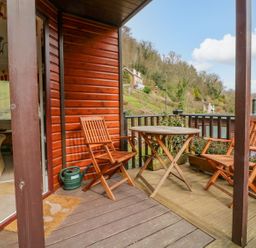 A wooden deck with a round table and two chairs outside a house with a view of hills at 22 Two Little Ducks in Lynton