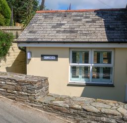 An exterior view of a house with a sign and stone wall at Hilldene in Treknow