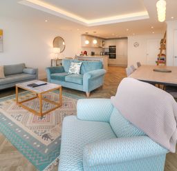 An open plan living room and kitchen with sofas and a dining table at Ameila's Point in St Ives