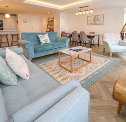 A living room with sofas a coffee table a dining table and chairs and a kitchen area with bar stools at Amelias Point in St Ives