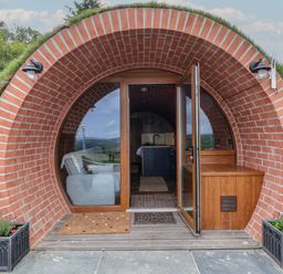 A round brick entrance with glass doors leading to a room with a sofa and kitchen at Rhosydd in Cyffylliog near Ruthin