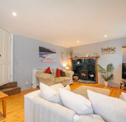 A living room with sofas a wood stove a television and a wooden table at Stone's Throw Cottage in Launceston