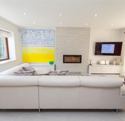 A living room with a white sectional sofa a wall-mounted television and a fireplace at The Arthouse in Ambleside