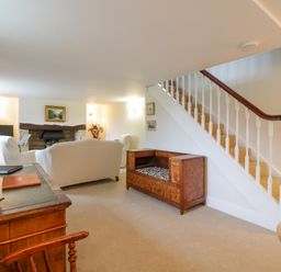 A living room with a fireplace sofas armchairs a wooden desk and a staircase at West View in Feltwell