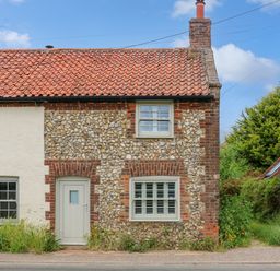 A cottage with a red tiled roof and pebble dash walls with white door and windows at Daisys Place in South Creake near Little Walsingham