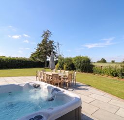 A garden with a hot tub and dining table at Daniels Farmhouse in Claines