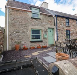 An outdoor view of the exterior of a house with seating at 2 Strand Cottages in Laugharne