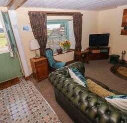 A living room with a sofa and television at 2 Strand Cottages in Laugharne