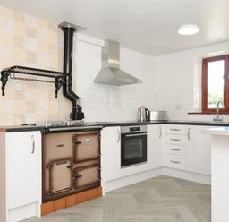 A kitchen with white cabinets black countertops a stove oven toaster kettle and a window at West Lee in Bude
