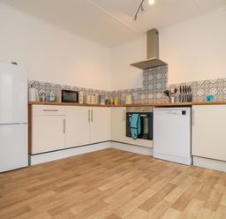 A kitchen with white cabinets wooden countertops patterned tile backsplash and various appliances including fridge microwave oven dishwasher and washing machine at Small Hillman in Perranporth