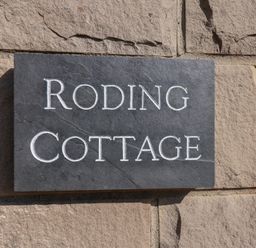 A stone plaque with the words Roding Cottage on a stone wall at Roding Cottage in Egton