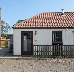 An exterior view of a single-story house with a tiled roof a wooden door and a wooden fence near Filey