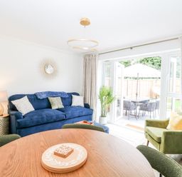 A living room with a blue sofa and green armchair next to glass doors opening to a patio at Pine Cottage in Wrentham