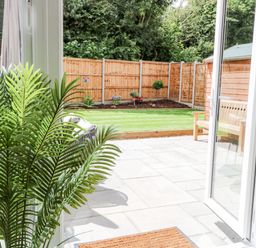 A view of a garden with a wooden fence patio plants and outdoor seating at Pine Cottage in Wrentham