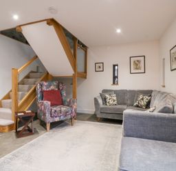 A living room with a staircase and seating at The Hay Barn in Huntley
