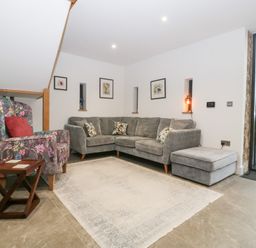 A living room with a sofa and chair at The Hay Barn in Huntley