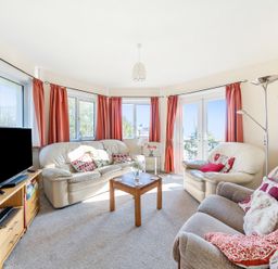 A living room with leather sofas a wooden coffee table a television on a wooden stand and red curtains at Bayview in Overcombe near Preston