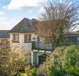 A house with a tiled roof and a balcony surrounded by bushes and trees at Bayview in Overcombe near Preston