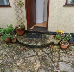 An entrance with flower pots and a doormat at Bridge Cottage in Budleigh Salterton