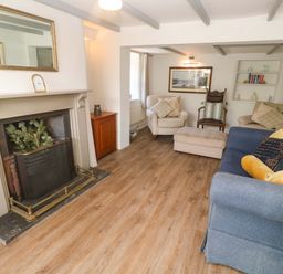 A living room with a fireplace and seating area at Greenways, Perranporth