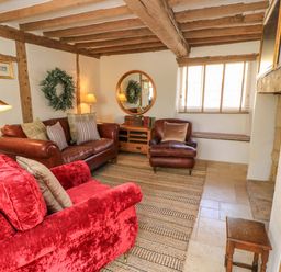A living room with a sofa and armchair at 8 Gloucester Street Winchcombe