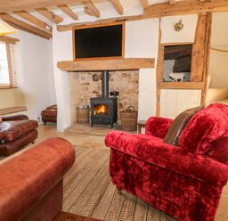 A living room with a fireplace and wooden beams at 8 Gloucester Street in Winchcombe