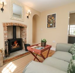A living room with a fireplace a sofa and a small table at The Alms House East in Forthampton near Tewkesbury