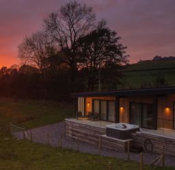 A modern house with a hot tub on the patio near trees at sunset at The Lookout in Longridge