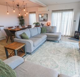 A living room with a sofa and dining area at Bay View in Portreath