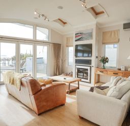 A living room with a leather sofa a fabric sofa wooden coffee table TV and fireplace at The Warren M45 in Abersoch
