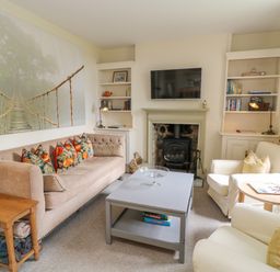 A living room with a sofa armchairs coffee table fireplace and bookshelf at Peartree in Colerne