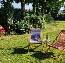 A garden with deck chairs and a table at Driftwood in Dartmouth