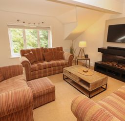 A living room with a sofa, coffee table, and television at Waterfall in Ambleside