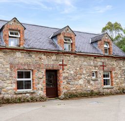 A stone cottage with a pathway and table at Orchard Barn in Wexford