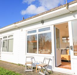 A white exterior of a house with two chairs and a small table outside near an open door at 418 Norton Park in Dartmouth